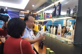 Ông Trần Hữu Linh, Tổng cục trưởng Tổng cục Quản lý thị trường hướng dẫn phân biệt hóa mỹ phẩm giả. (Ảnh: Xuân Quảng/Vietnam+)