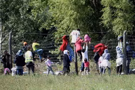 Người di cư vượt qua hàng rào tại khu vực làng Roszke, biên giới Hungary-Serbia. (Ảnh: AFP/TTXVN)
