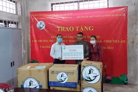Ông Trần Đức Hiển, Phó Chủ nhiệm Ủy ban về Người Việt Nam ở nước ngoài TP.HCM (ngoài cùng, bên trái) trao tượng trưng kinh phí cho đại diện trường Tiểu học Hữu nghị tỉnh Champasak của Lào. (Ảnh: TTXVN phát)