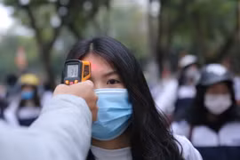 Kiểm tra thân nhiệt của học sinh khi đến trường. (Ảnh: Hoàng Hiếu/TTXVN)