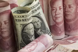 Đồng USD (giữa) và đồng Nhân dân tệ của Trung Quốc. (Ảnh: AFP/TTXVN)