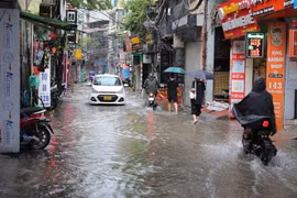Người dân phố Triều Khúc ở Hà Nội đi lại khó khăn do mưa ngập. (Ảnh: Hoàng Hiếu/TTXVN)