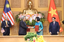 Tổng Giám đốc TTXVN Vũ Việt Trang và Tổng Biên tập Hãng thông tấn quốc gia Malaysia (BERNAMA) Khairdzir Md Yunus trao đổi Thỏa thuận hợp tác nghiệp vụ giữa 2 hãng thông tấn. (Ảnh: Dương Giang/TTXVN)