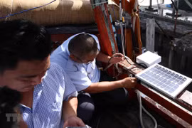 Thanh tra ngành thủy sản kiểm tra thiết bị giám sát hành trình khai thác thủy hải sản lắp đặt trên tàu cá của ngư dân. (Ảnh: Vũ Sinh/TTXVN)