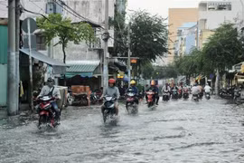 Người dân di chuyển giữa làn nước trên đường Huỳnh Tấn Phát ở quận 7. (Ảnh: Hồng Giang/TTXVN)