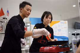 Đầu bếp Christine Ha (phải) và đầu bếp Tuyết Phạm - á quân MasterChef Việt Nam 2015 truyền cảm hứng nấu ăn cho các học viên. (Ảnh: Trần Lê Lâm/TTXVN)