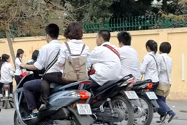 Học sinh đi xe máy dàn hàng ngang, không đội mũ bảo hiểm. (Ảnh: Văn Điệp/TTXVN)