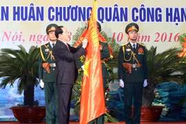 Chủ tịch nước Trần Đại Quang gắn Huân chương Quân công hạng Nhất lên lá cờ truyền thống của lực lượng vũ trang Thủ đô. (Ảnh: Nhan Sáng/TTXVN)