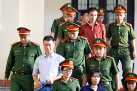 Bị cáo Phan Sào Nam (áo trắng) cùng các bị cáo được cơ quan chức năng dẫn giải ra tòa. (Ảnh: Trung Kiên/TTXVN)