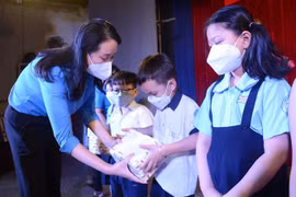 Đại diện "Quỹ xã hội từ thiện Tấm lòng vàng" trao quà và học bổng cho các em học sinh là con em công nhân Công ty TNHH May thêu giày An Phước có hoàn cảnh khó khăn. (Ảnh: Thanh Vũ/TTXVN)