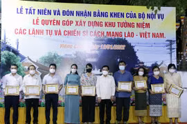 Bộ trưởng Nội vụ Lào, ông Thongchan Manixay (giữa) với các cá nhân và tập thể người Việt có nhiều thành tích trong công tác cứu trợ và vận động cứu trợ cho người dân Lào gặp thiên tai, dịch bệnh trong thời gian qua. (Ảnh: Phạm Kiên/TTXVN)
