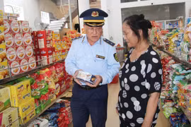 Cán bộ Quản lý thị trường hướng dẫn người tiêu dùng về các thông tin hàng hóa. (Ảnh: qltt.vn)