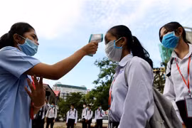 Kiểm tra thân nhiệt phòng lây nhiễm COVID-19 trong lớp học tại Phnom Penh (Campuchia). (Ảnh: AFP/TTXVN)
