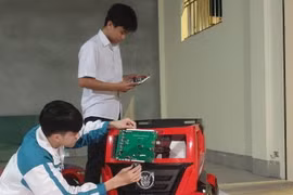 Em Phạm Đăng Minh (đứng) và Hoàng Văn Đồng nghiên cứu thực hiện đề tài. (Ảnh: Hải Yến/TTXVN)