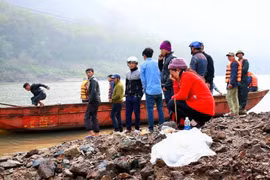 Người thân và những người bạn của các lao động bốc vác bên sông tìm kiếm các nạn nhân. (Ảnh: Phạm Hồng Ninh/TTXVN)