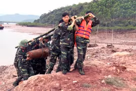 Lực lượng chức năng xử lý di chuyển quả bom đến nơi an toàn. (Ảnh: Nguyễn Hoàng/TTXVN)