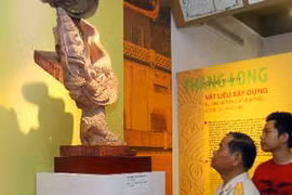 Khách tham quan chiêm ngưỡng ngói lợp góc tạo hình rồng thời Lý thế kỷ 11-12. (Ảnh: Thanh Tùng.TTXVN)