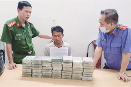 Đối tượng Chang A Sang (SN 1995), trú tại bản Chuyên Gia 2, xã Nậm Kè, huyện Mường Nhé cùng tang vật 60 bánh heroin tại Cơ quan điều tra. (Ảnh: TTXVN phát)
