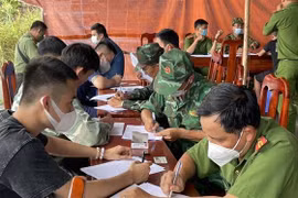 Bộ đội Biên phòng và Công an tỉnh Tây Ninh làm các thủ tục tiếp nhận người lao động tự do tại Campuchia trở về nước. (Ảnh: TTXVN phát)