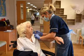 Nhân viên y tế tiêm vaccine phòng COVID-19 cho một cụ bà ở Wigan (Anh). (Ảnh: AFP/TTXVN)