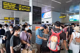 Hành khách xếp hàng làm thủ tục an ninh soi chiếu hàng không trước khi lên máy bay. (Ảnh: PV/Vietnam+)