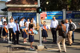 Học sinh trường Trung học cơ sở Lê Quý Đôn sử dụng đèn tín hiệu dành cho người đi bộ tại cổng trường. (Ảnh: PV/Vietnam+)