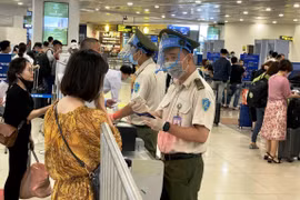 Nhân viên an ninh hàng không kiểm tra thông tin hành khách trước khi vào điểm soi chiếu an ninh. (Ảnh: CTV/Vietnam+)