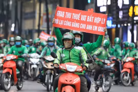 Các tài xế Grab với những băng rôn khẩu hiệu "Grab thu thuế VAT bất hợp lý". (Ảnh: Thành Đạt/TTXVN)
