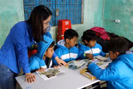 Thanh niên TTXVN cùng các em học sinh đọc những cuốn sách trong "Tủ sách Đinh Hữu Dư". (Ảnh: Nguyên Lý/TTXVN)
