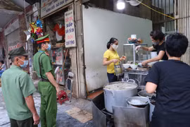 Công an phường Hàng Mã nhắc nhở nhân dân thực hiện nghiêm việc giãn cách, đeo khẩu trang để phòng, chống dịch COVID-19. (Ảnh: Doãn Tấn/TTXVN)