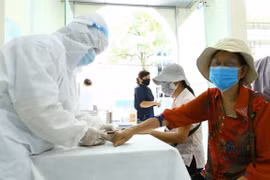 Nhân viên y tế lấy mẫu xét nghiệm nhanh cho người về từ Đà Nẵng. (Ảnh: Minh Quyết/TTXVN)