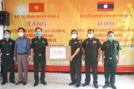 Đại diện lãnh đạo Bộ Tư lệnh Quân khu 4 (bên trái) trao tặng vật tư y tế cho đại diện quân đội Lào. (Ảnh: TTXVN)