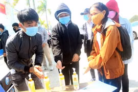 Các thí sinh đều nghiêm túc rửa tay bằng dung dịch sát khuẩn trước khi vào làm thủ tục thi. (Ảnh: Trịnh Bang Nhiệm/TTXVN)