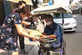 Trao quà cho người bán vé số dạo. (Ảnh: Lê Thúy Hằng/TTXVN)