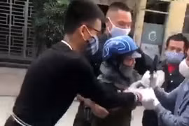Lực lượng chức năng khống chế người phụ nữ bán rau. (Ảnh cắt từ clip)