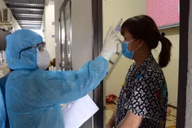 Kiểm tra thân nhiệt cho người dân. (Ảnh minh họa: Quốc Dũng/TTXVN)