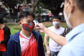 Kiểm tra thân nhiệt cho khách vào thăm quan Di tích lịch sử Văn Miếu-Quốc Tử Giám. (Ảnh: Thành Đạt/TTXVN)