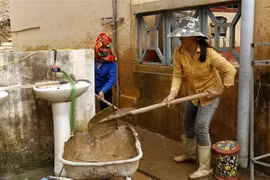 Phụ huynh học sinh cùng giáo viên nhà trường dọn vệ sinh khuôn viên trường học để học sinh nhanh chóng trở lại học tập. (Ảnh: Quốc Khánh/TTXVN)