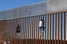 Hai cậu bé cố gắng trèo qua bức tường biên giới giữa Mỹ và Mexico tại Ciudad Juarez, Mexico. (Nguồn: AFP/TTXVN)