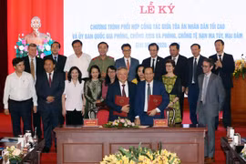 Bộ trưởng Bộ Lao động-Thương binh và Xã hội Đào Ngọc Dung và Chánh án Tòa án nhân dân tối cao Nguyễn Hòa Bình trao biên bản sau khi ký kết Chương trình phối hợp công tác. (Ảnh: Anh Tuấn/TTXVN)