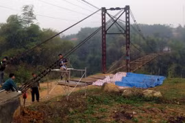 Công nhân Công ty trách nhiệm hữu hạn Thành Long đang khẩn trương sửa chữa cầu treo Bình Yên. (Ảnh Quang Đán/TTXVN)