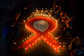 Những người tình nguyện xếp nến thành hình ruybăng đỏ nhân Ngày Thế giới phòng chống AIDS (1/12) tại Siliguri, Ấn Độ. (Ảnh: AFP/TTXVN)