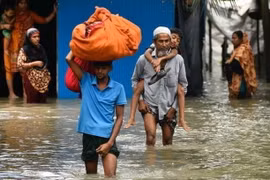 Người dân sơ tán khỏi vùng ngập lụt tại Feni, Chittagong, Bangladesh, ngày 23/8. (Ảnh: Getty Images/TTXVN)