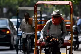 Người dân đội mũ và khăn để tránh nắng nóng tại New Delhi, Ấn Độ. (Ảnh: AFP/TTXVN)