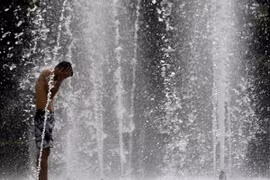 Người dân làm mát tại một đài phun nước ở Seville, Tây Ban Nha. (Ảnh: AFP/TTXVN)