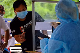 Lực lượng y tế kiểm tra lại thông tin của một tài xế tại khu vực khai báo y tế, xuất trình các giấy tờ liên qua khi đi qua trạm kiểm soát COVID-19 trên quốc lộ 20, tỉnh Lâm Đồng. (Ảnh: Nguyễn Dũng - TTXVN)
