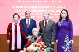 Chủ tịch nước Nguyễn Xuân Phúc và các đại biểu tại Lễ trao tặng huy hiệu 75 năm tuổi Đảng cho bà Nguyễn Thị Bình, nguyên Ủy viên Trung ương Đảng, nguyên Phó Chủ tịch nước CHXHCN Việt Nam. (Ảnh: Thống Nhất/TTXVN)
