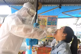 Lấy mẫu xét nghiệm COVID-19 của những người làm việc tại bến xe Bình Dương. (Ảnh: Văn Hướng/TTXVN)