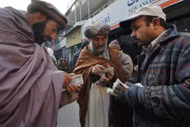 Người dân Afghanistan đổi tiền đôla Mỹ sang đồng nội tệ tại điểm giao dịch ngoại hối ở một khu chợ của Kabul. (Ảnh: AFP/TTXVN)