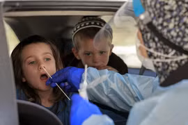 Nhân viên y tế lấy mẫu xét nghiệm COVID-19 cho một em nhỏ tại Jerusalem ngày 29/7/2021. (Ảnh: AFP/TTXVN)